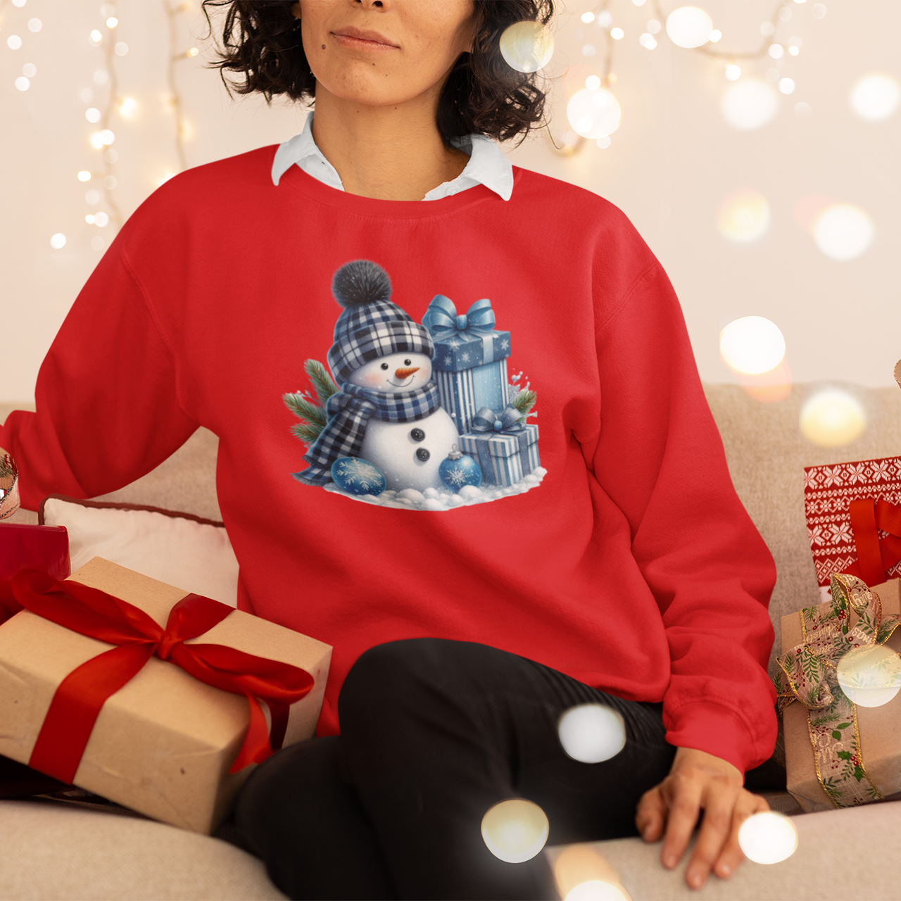 Person wearing a red Christmas sweater with a snowman design, surrounded by festive decorations and presents.