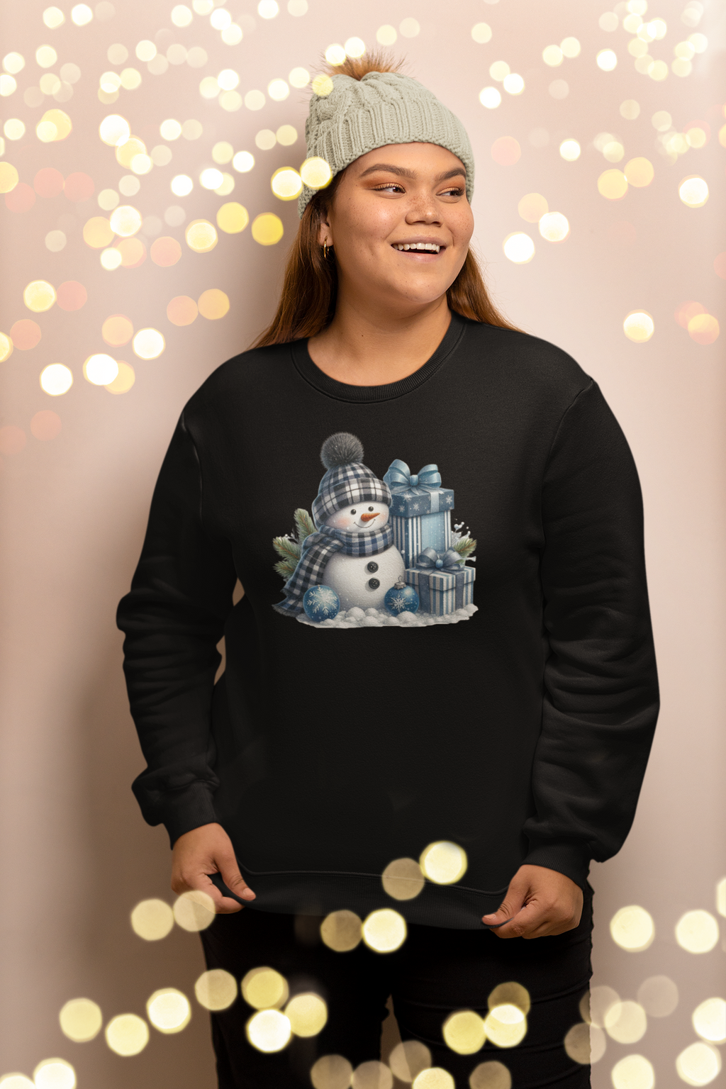 Person wearing a black sweatshirt with a snowman and gift design, standing against a festive light background.