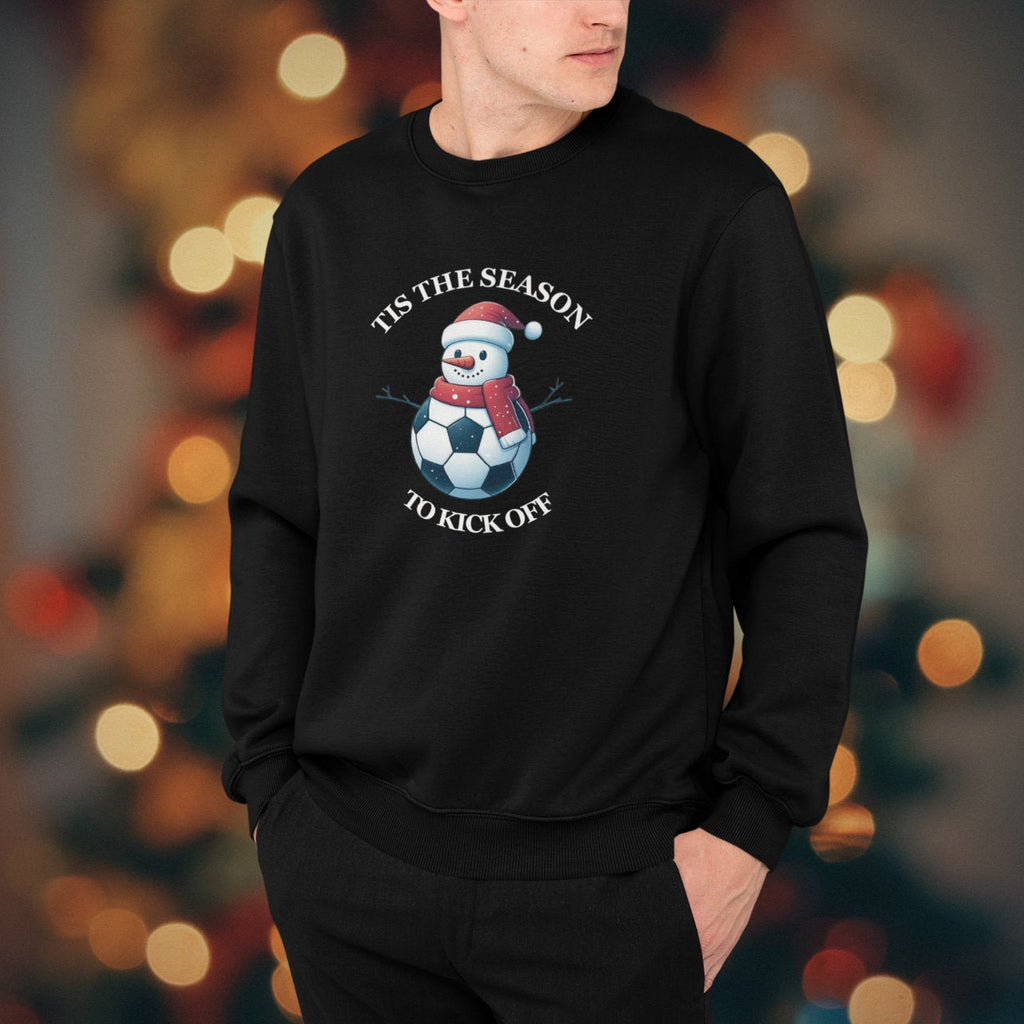 Person wearing a black sweatshirt with a Christmas-themed design in front of a blurred festive background.