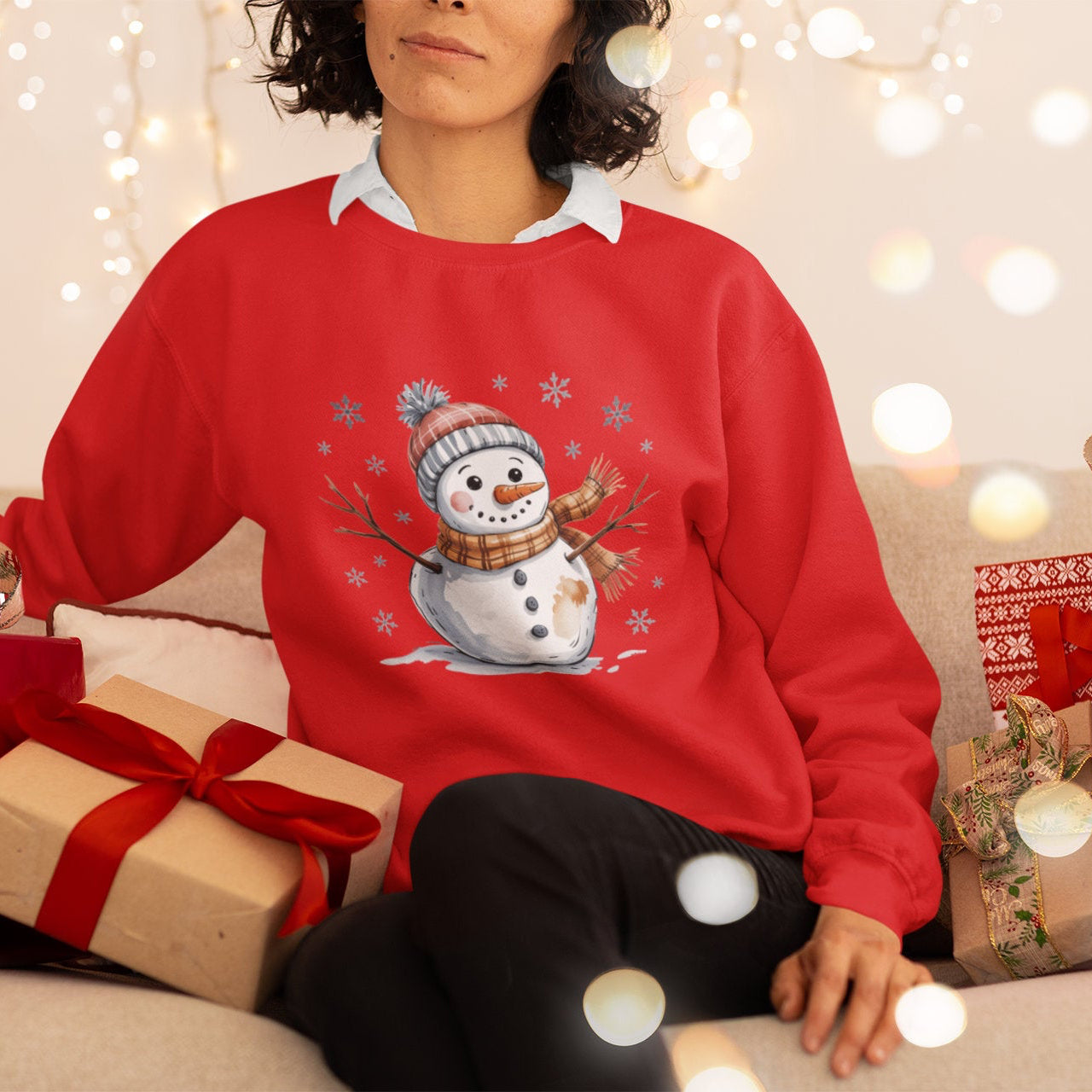 Person wearing a red Christmas sweater with a snowman design, surrounded by festive decorations and gifts.