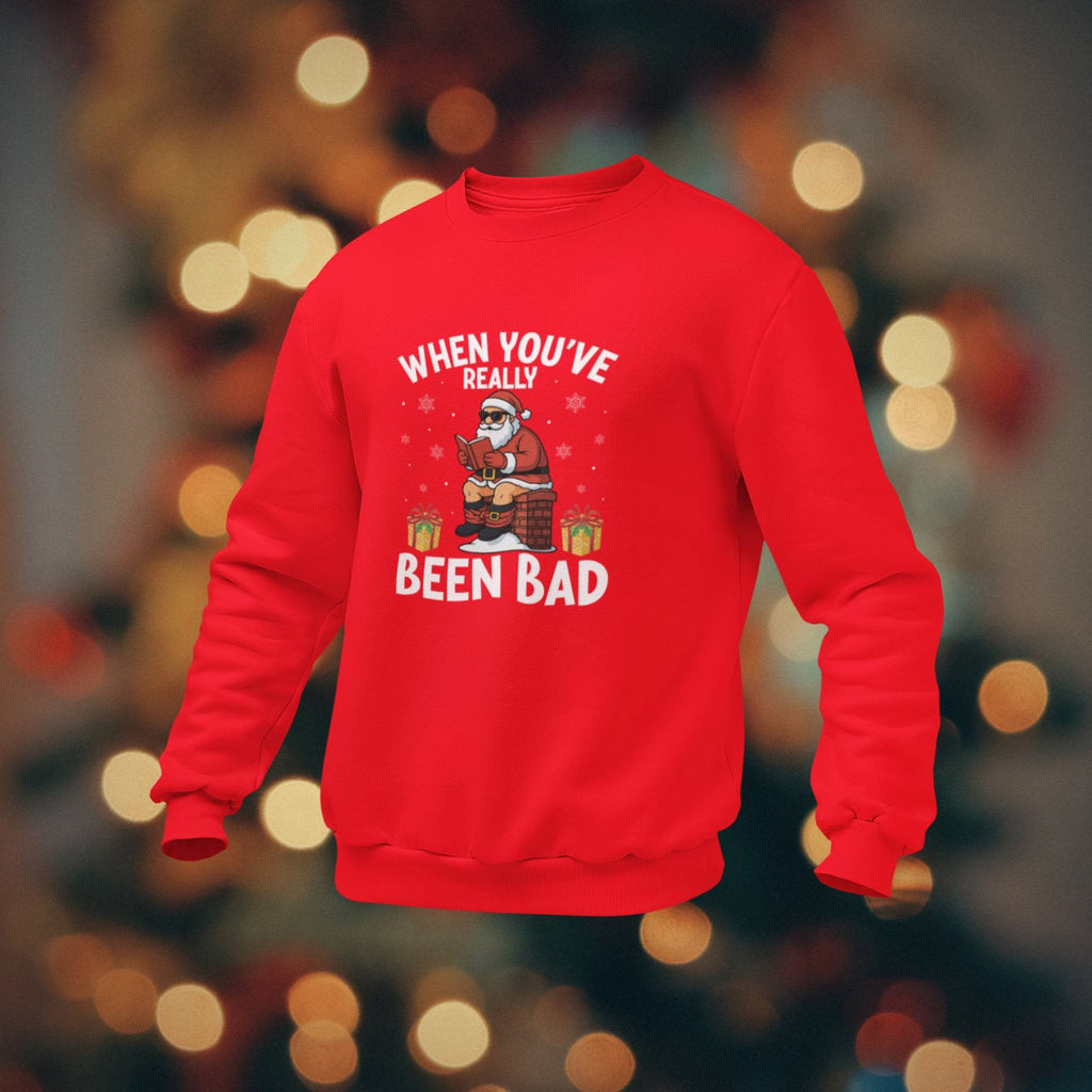 Red sweatshirt with Christmas-themed text and graphics on a blurred festive background