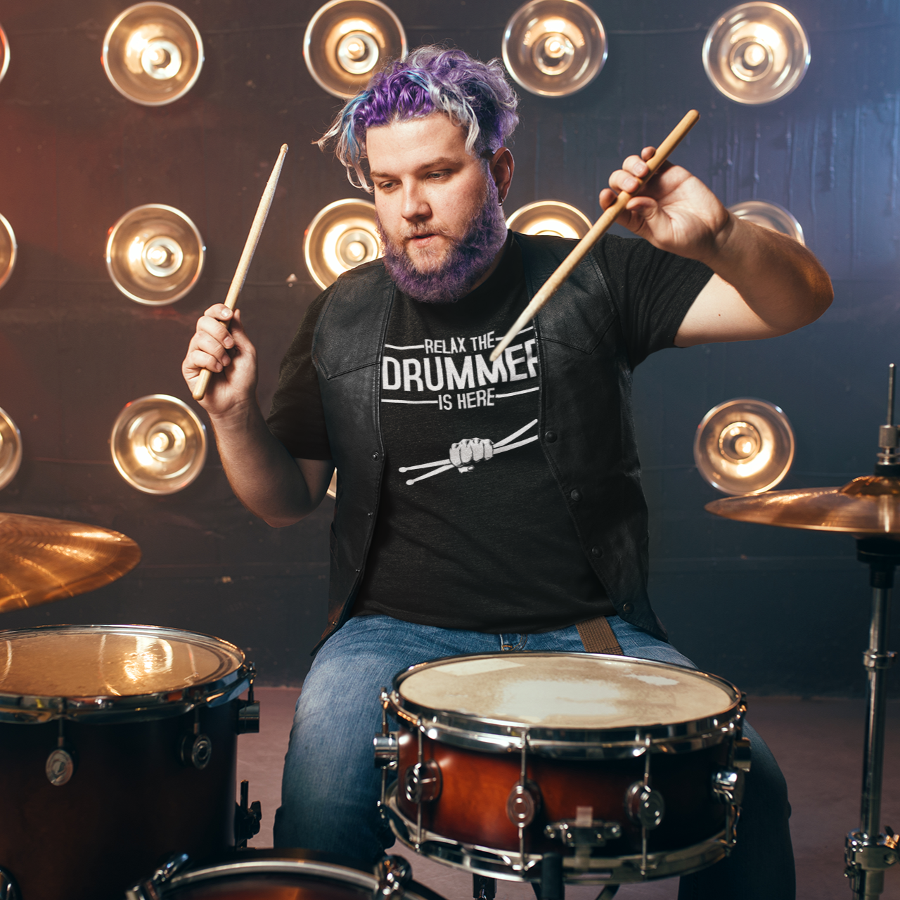 Man playing drums with a microphone stand and lights in the background