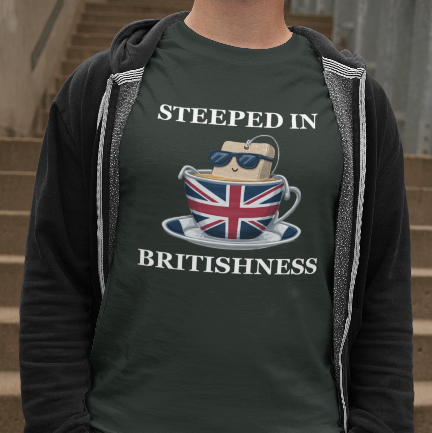 Person wearing a green t-shirt with 'Steeped in Britishness' design, standing on steps.
