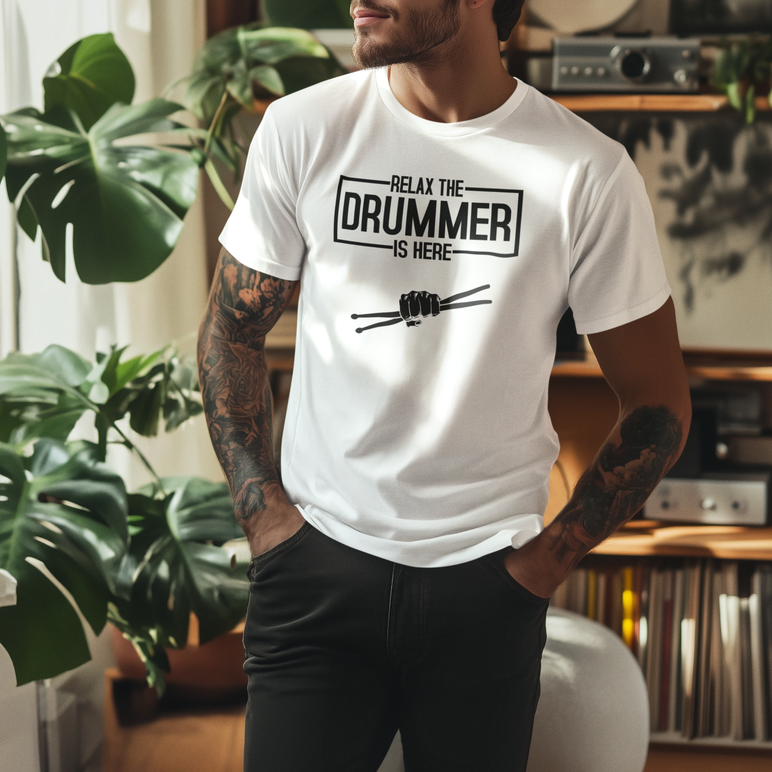 Man wearing a white t-shirt with 'Relax, the drummer is here' text in a room with plants and records.