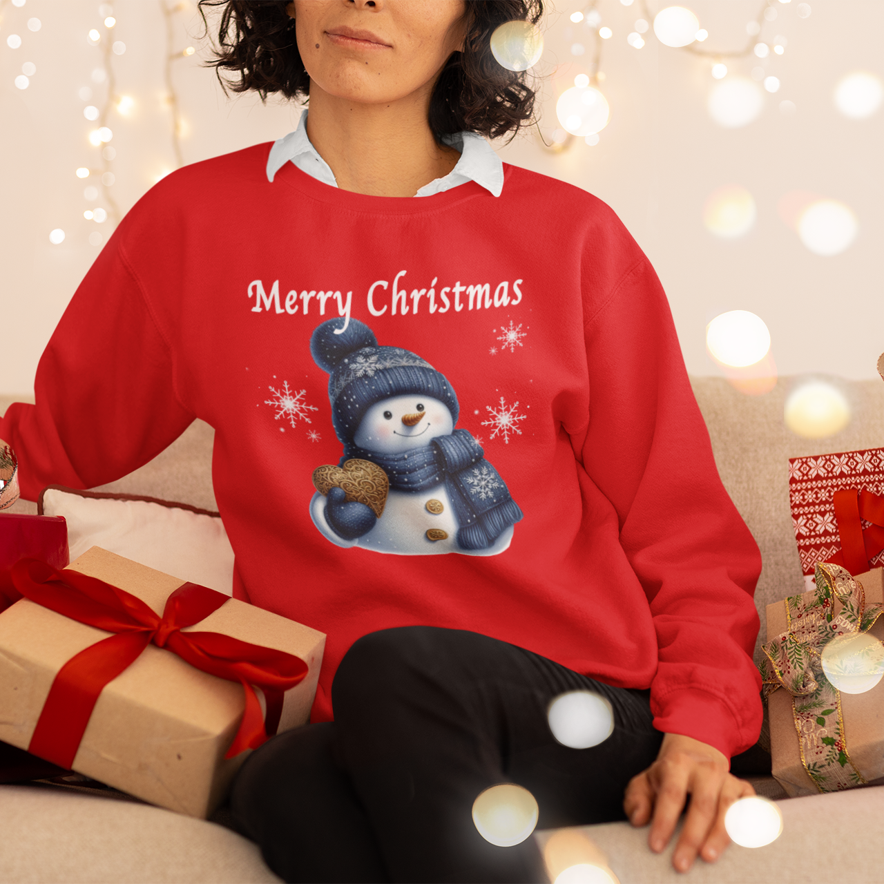 Person wearing a red 'Merry Christmas' sweater with a snowman design, surrounded by Christmas presents and lights.