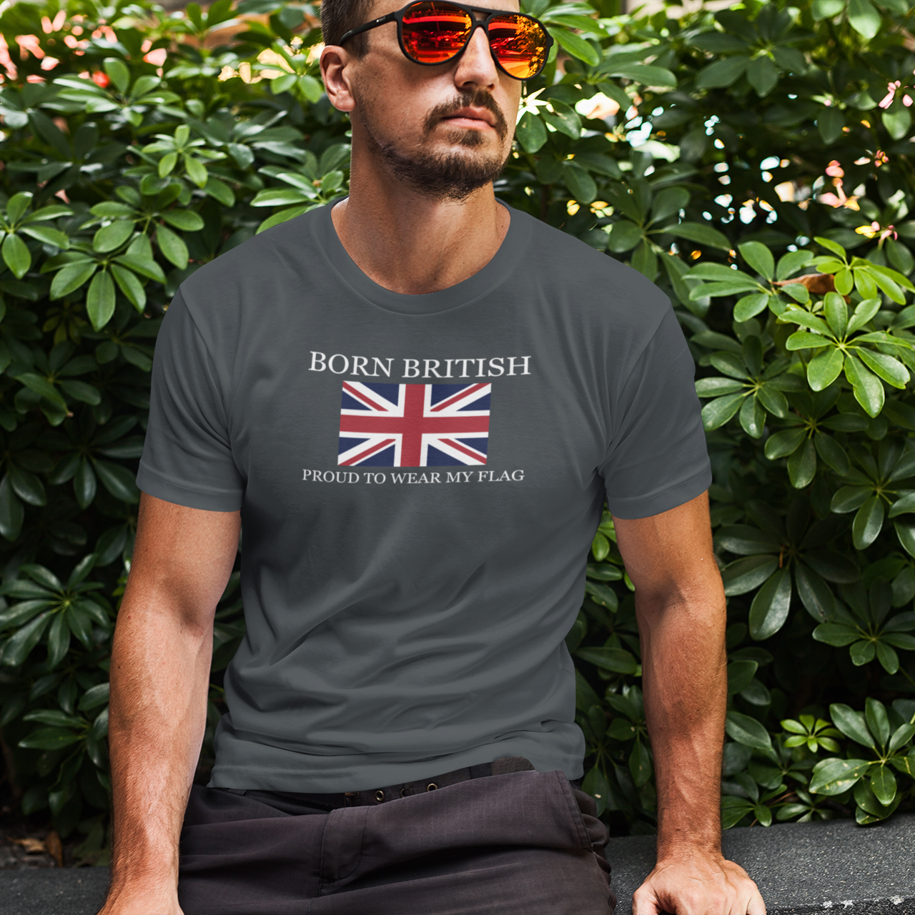 Man wearing a t-shirt with 'Born British' text and Union Jack design, sitting outdoors.