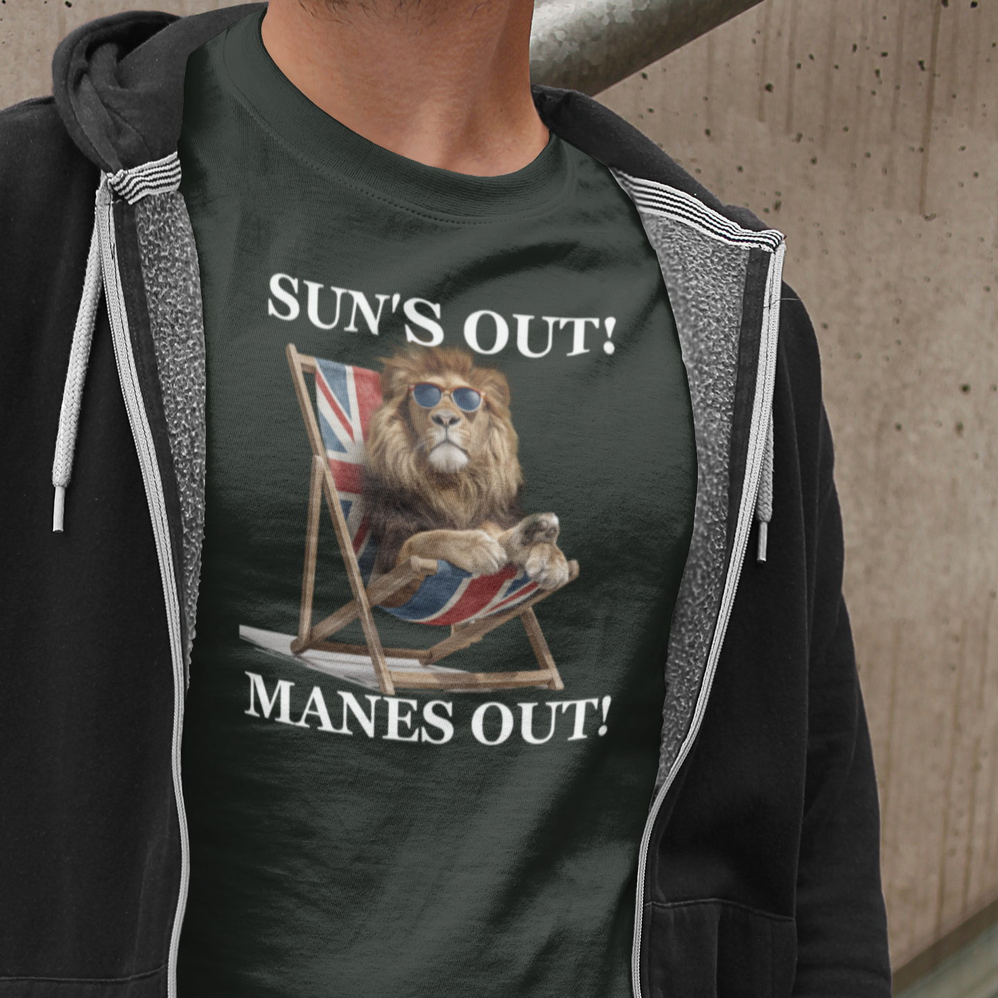 Person wearing a t-shirt with a graphic design and text, standing against a concrete wall.