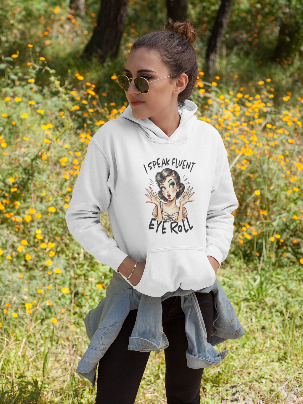 Woman wearing a white hoodie with a graphic design in a field of yellow flowers