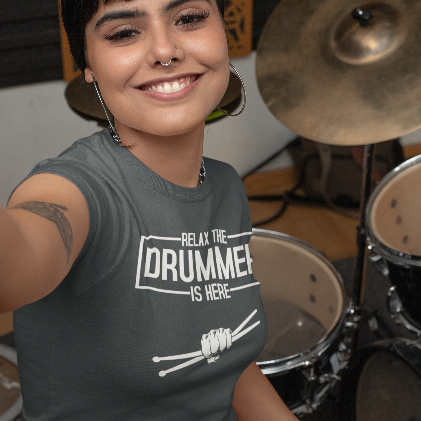 Person wearing a t-shirt with 'Relax, the drummer is here' text in front of a drum set.