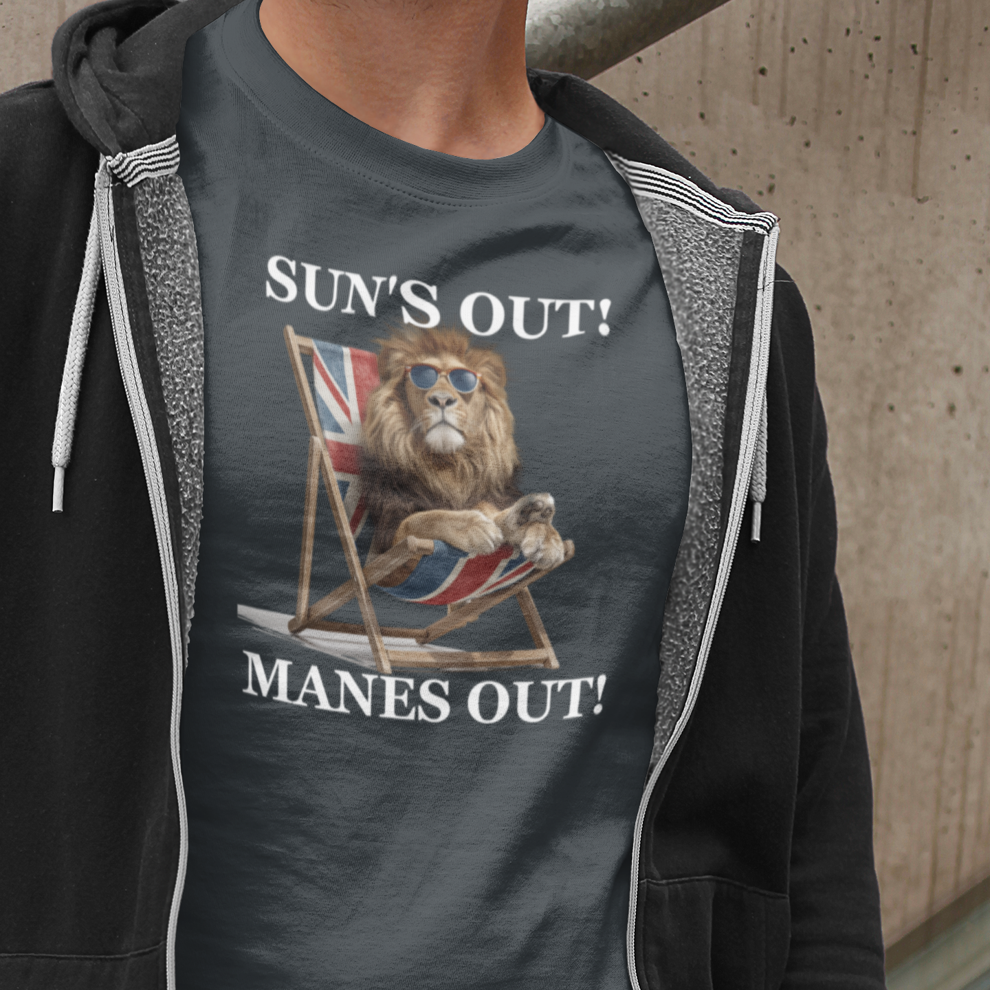 Person wearing a t-shirt with a graphic design and text 'SUN'S OUT! MANES OUT!' against a concrete wall.