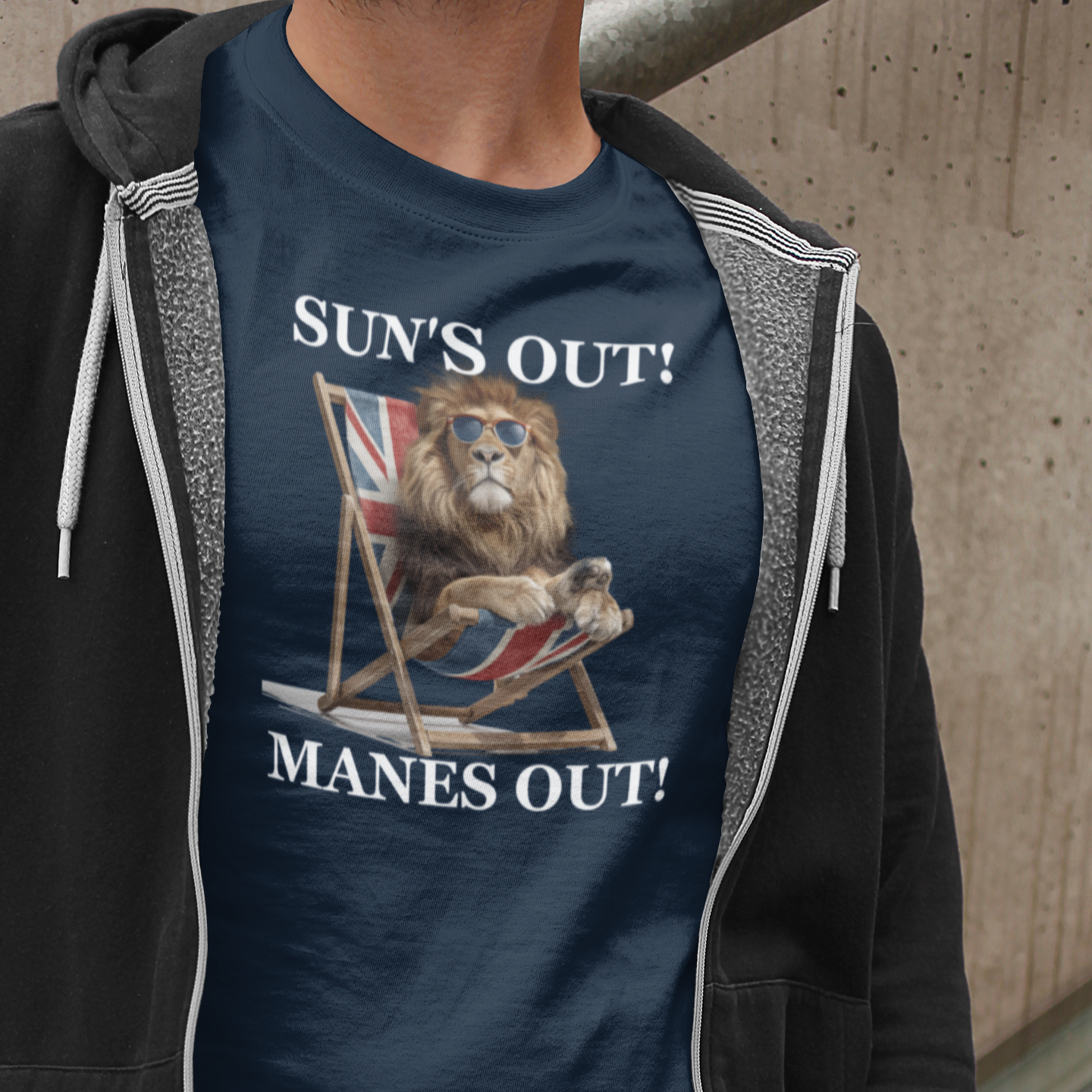 Person wearing a navy blue t-shirt with a graphic design and text, standing against a concrete wall.