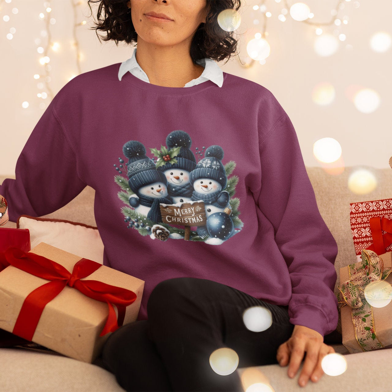 Person wearing a purple Christmas sweater with snowman design, surrounded by festive decorations and presents.