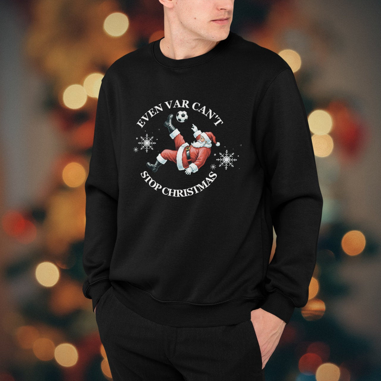 Person wearing a black sweatshirt with a Christmas design in front of a blurred festive background.