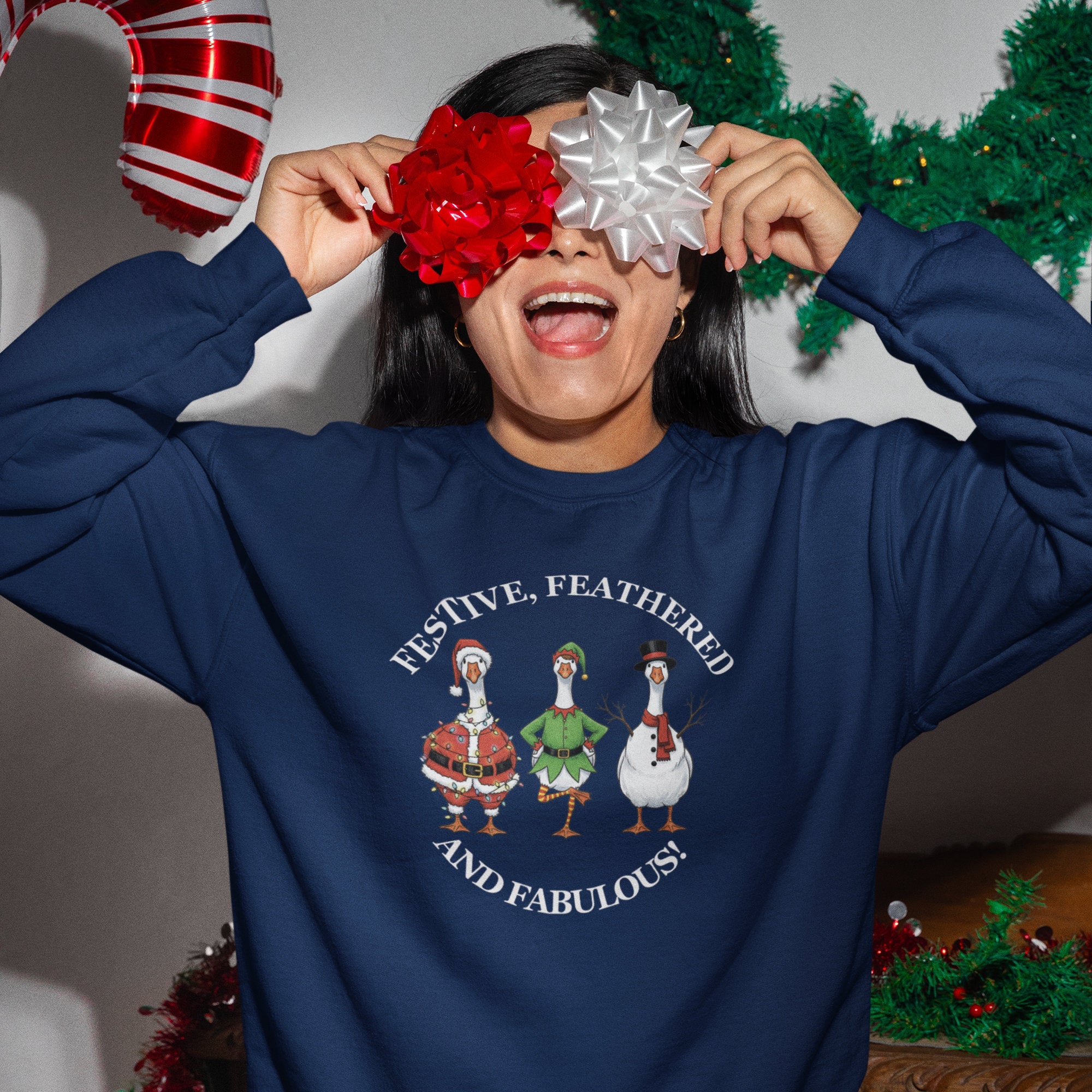 Female wearing a blue sweatshirt with Christmas-themed design, surrounded by festive decorations.