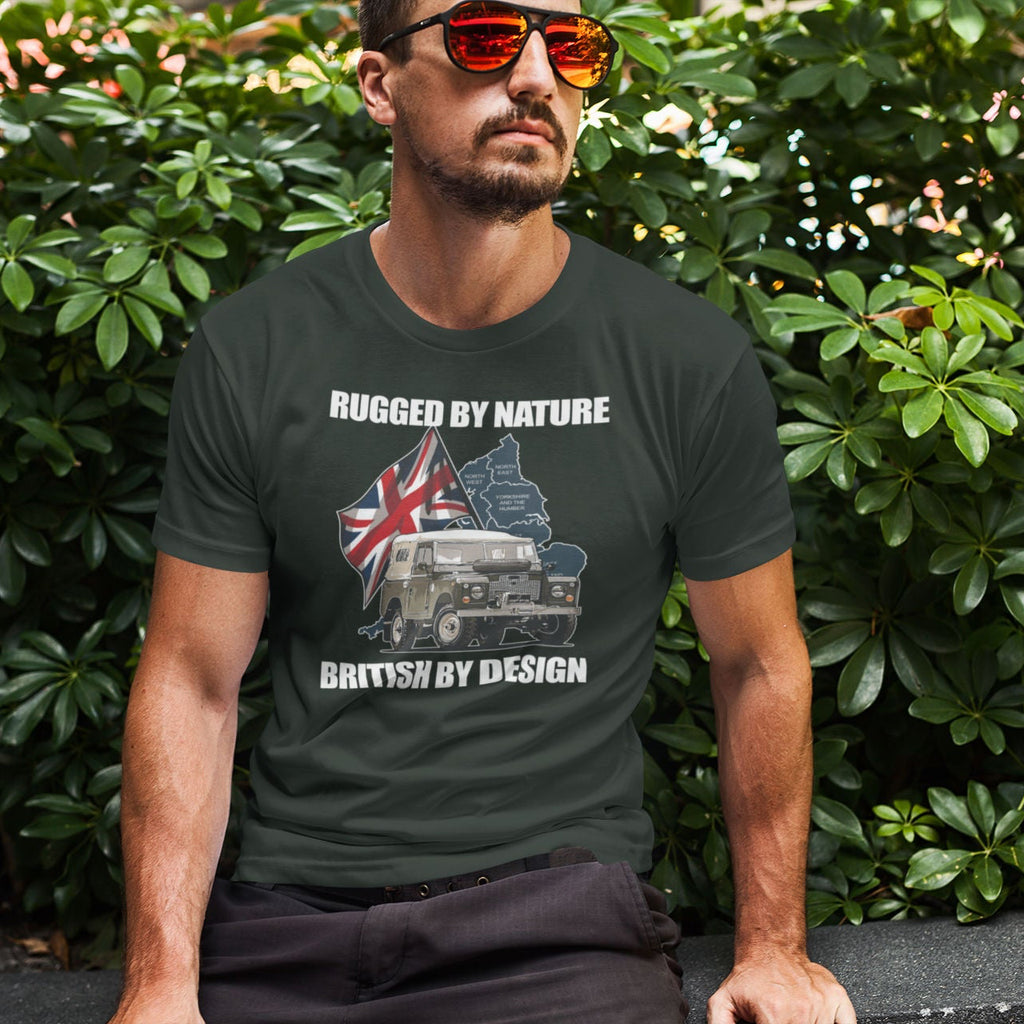 Man wearing a t-shirt with a graphic design sitting among green bushes.