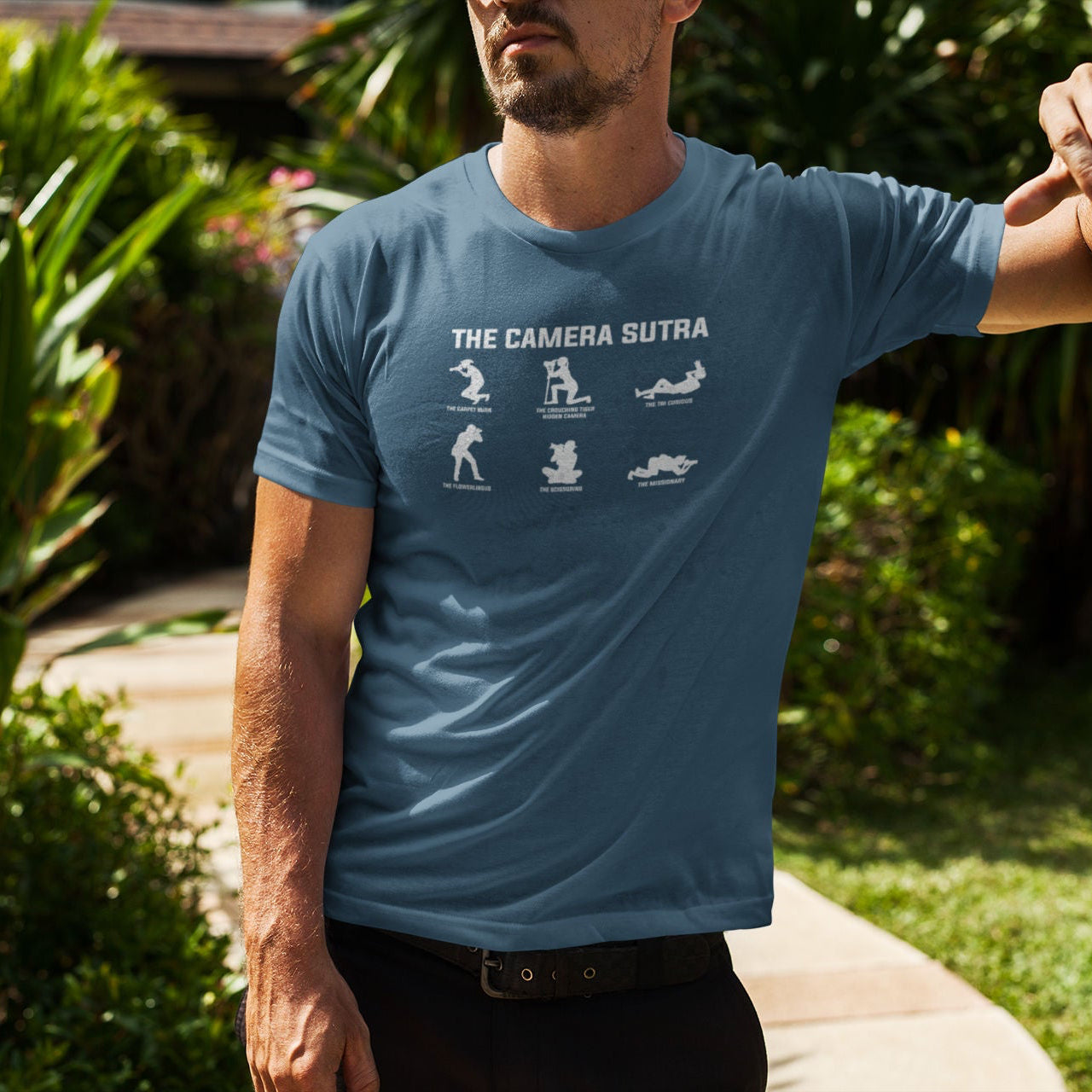 Man wearing a blue t-shirt with 'The Camera Sutra' design outdoors.