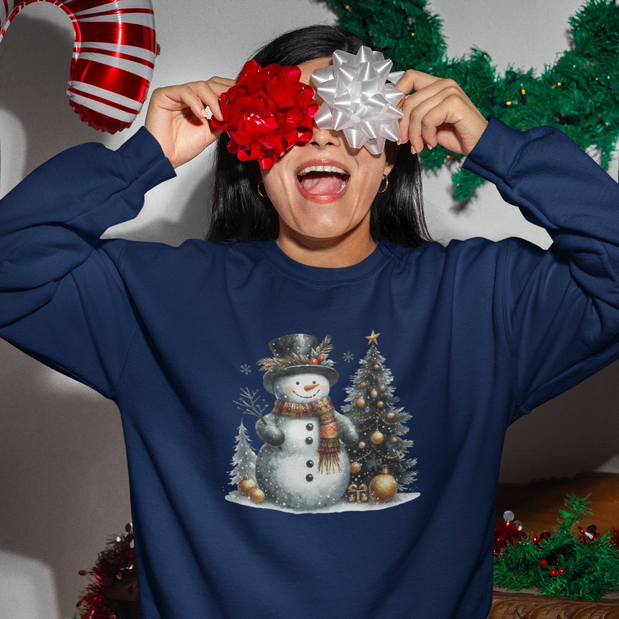 Person wearing a blue sweatshirt with a snowman design, holding Christmas decorations.