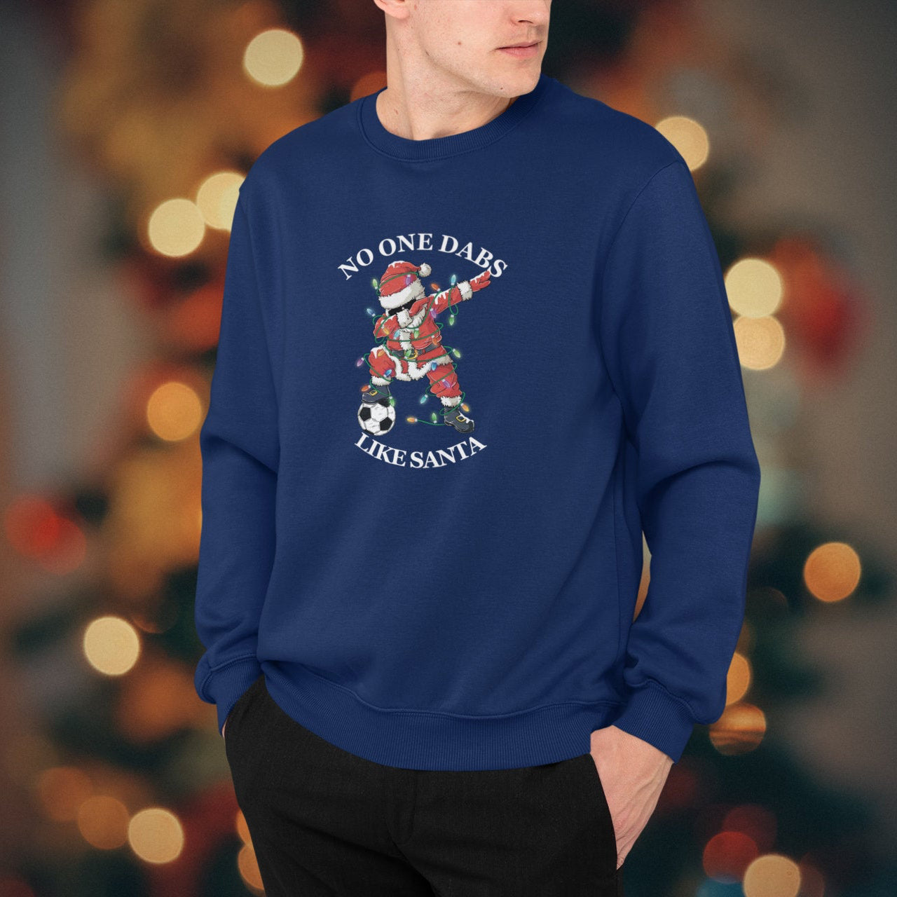 Person wearing a blue sweatshirt with a graphic design in front of a blurred festive background