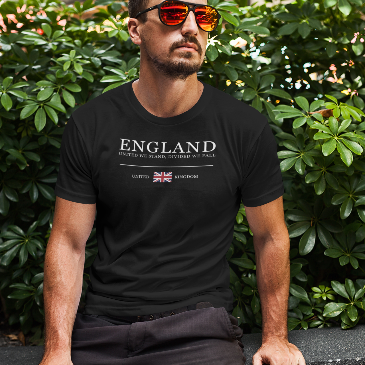 Man wearing a black t-shirt with 'ENGLAND' text and British flag, sitting outdoors.