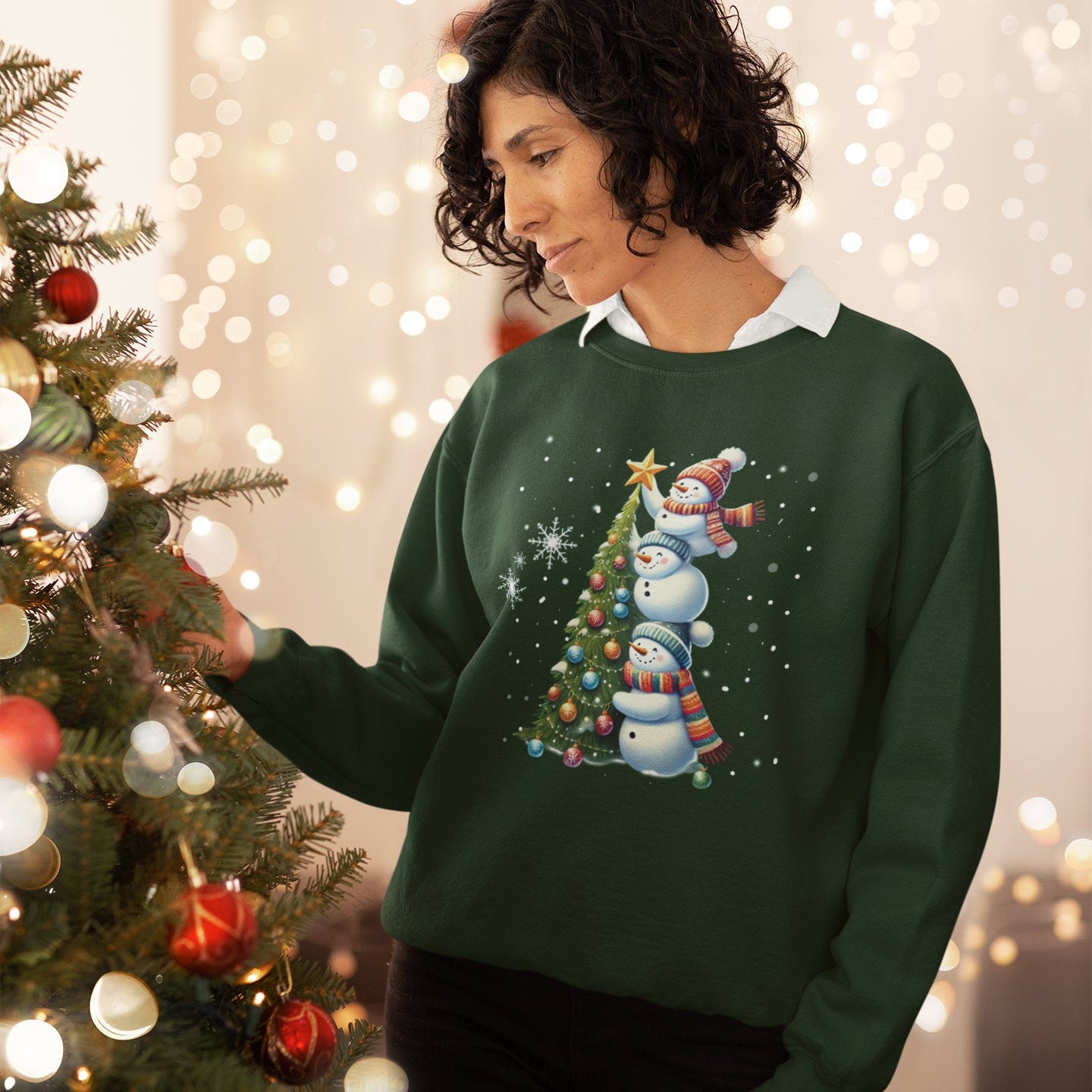 Female wearing a green sweater with a Christmas tree design, standing next to a decorated Christmas tree.