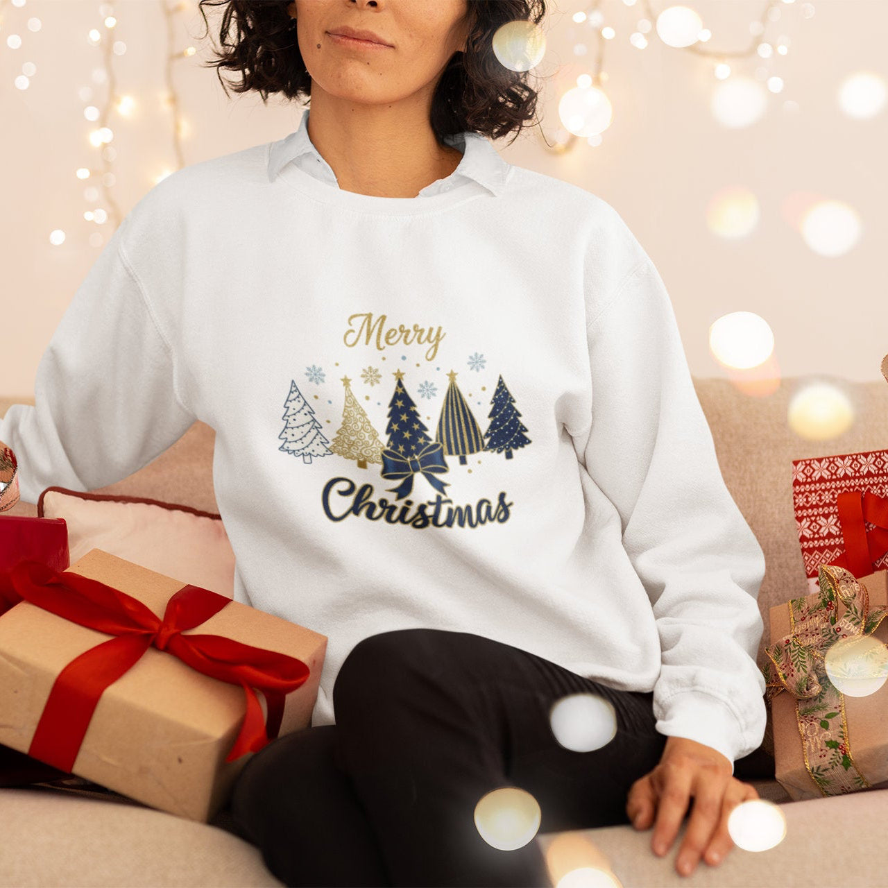 Person wearing a white sweatshirt with Christmas design surrounded by gift boxes and lights